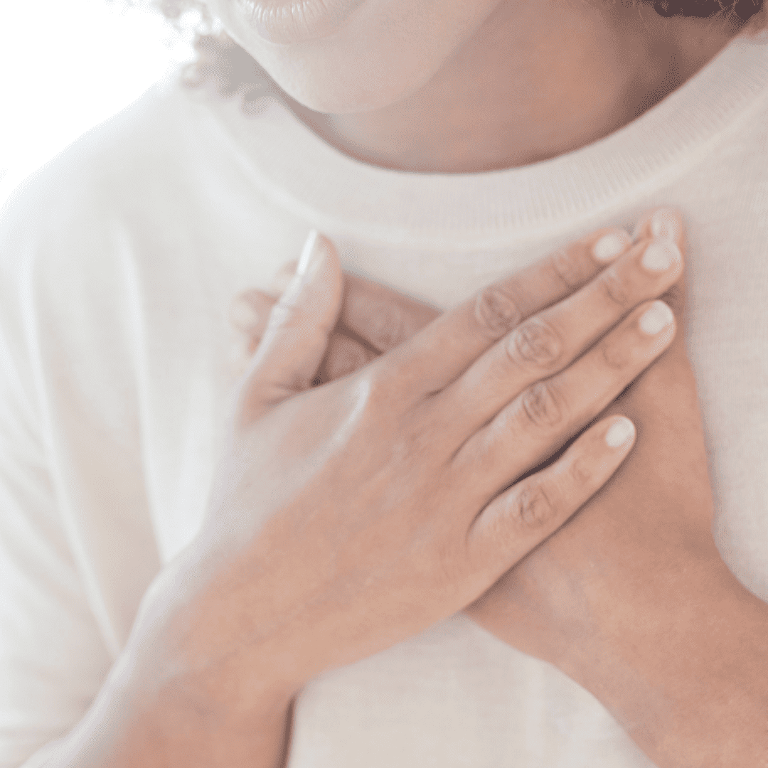 Female with two hands on centre of chest trying to catch her breath